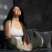 Woman meditating on couch, eyes closed, enjoying sunbeam.