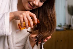 Applying hair oil for smooth, glossy strands.