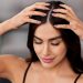 Woman performing a calming scalp massage with eyes closed.
