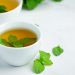 Brewed herbal mint tea in a white cup with fresh mint leaves