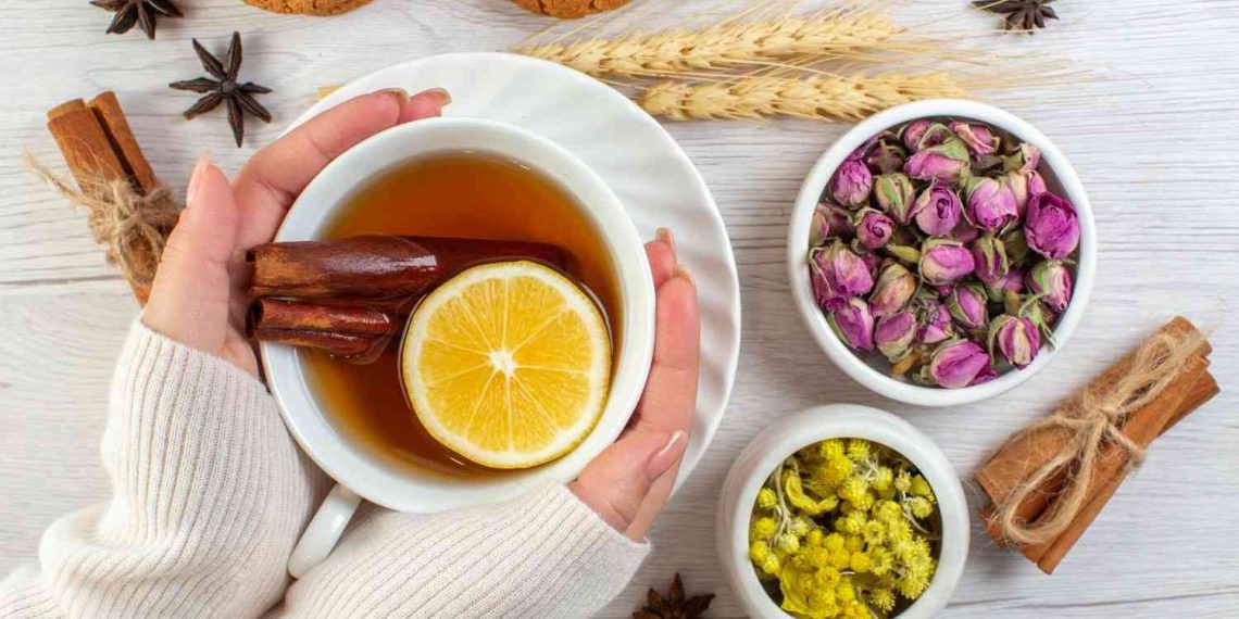 Cozy herbal tea with lemon and cinnamon, accompanied by dried flowers and cookies.