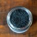 Jar filled with activated charcoal granules on wooden table.