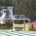 Pitcher and glass of apple juice on a checkered table.