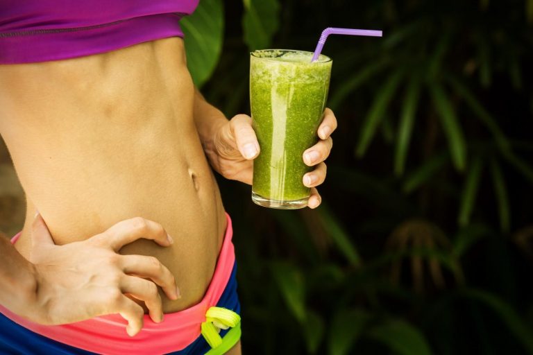 Athletic woman holding a healthy green smoothie
