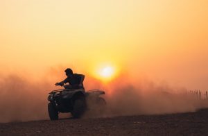 ATV rider kicking up dust at sunset.