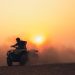 ATV rider kicking up dust at sunset.