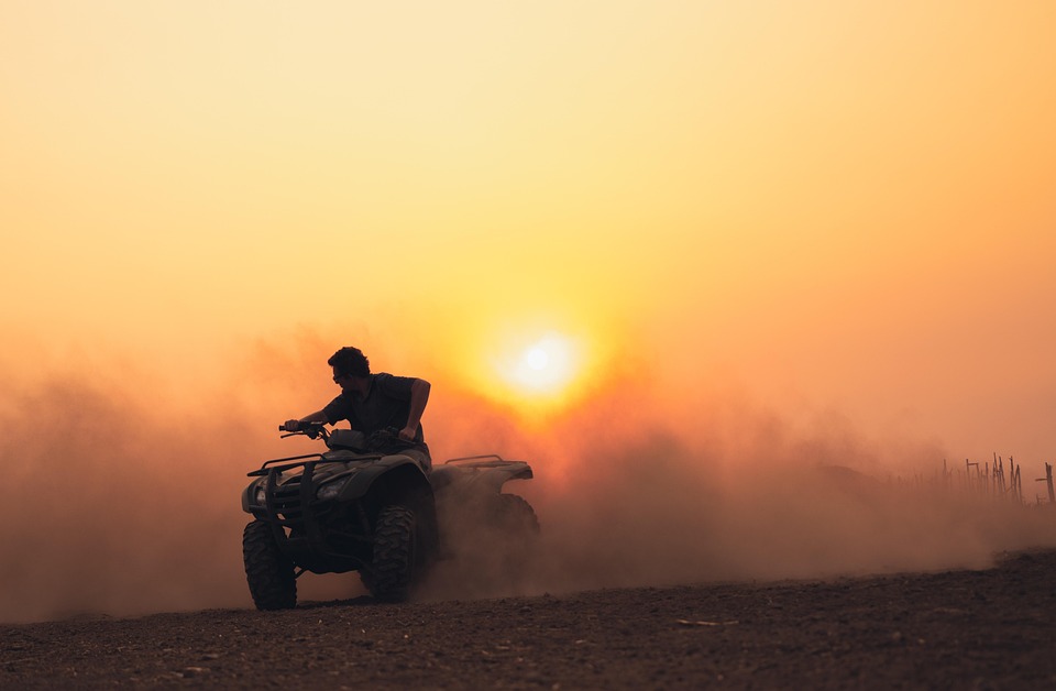 ATV rider kicking up dust at sunset.