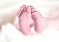 Newborn baby feet on soft white blanket.