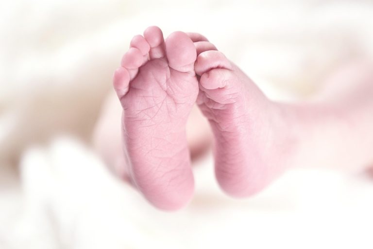 Newborn baby feet on soft white blanket.