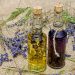 Two glass bottles of essential oil surrounded by dried lavender sprigs on burlap.