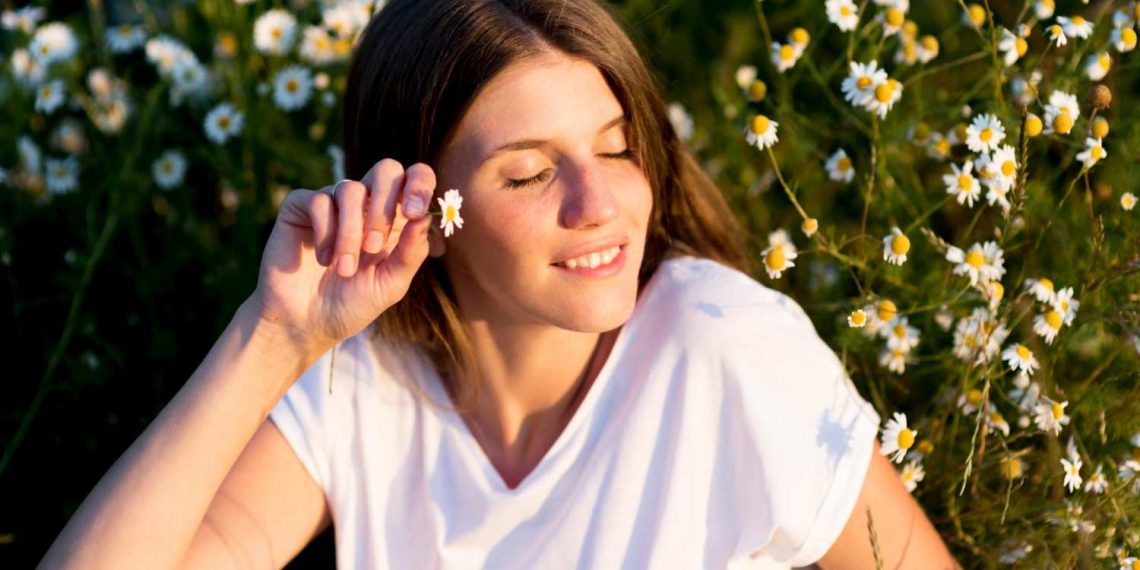 Young woman enjoying a sunny day among blooming daisies.