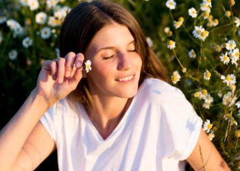 Young woman enjoying a sunny day among blooming daisies.
