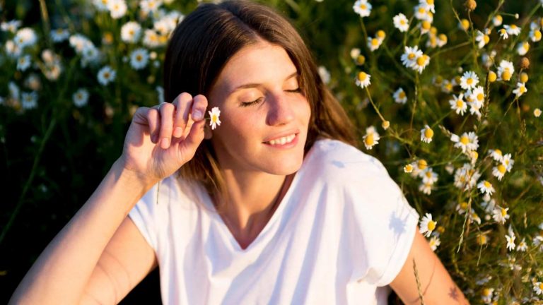 Young woman enjoying a sunny day among blooming daisies.