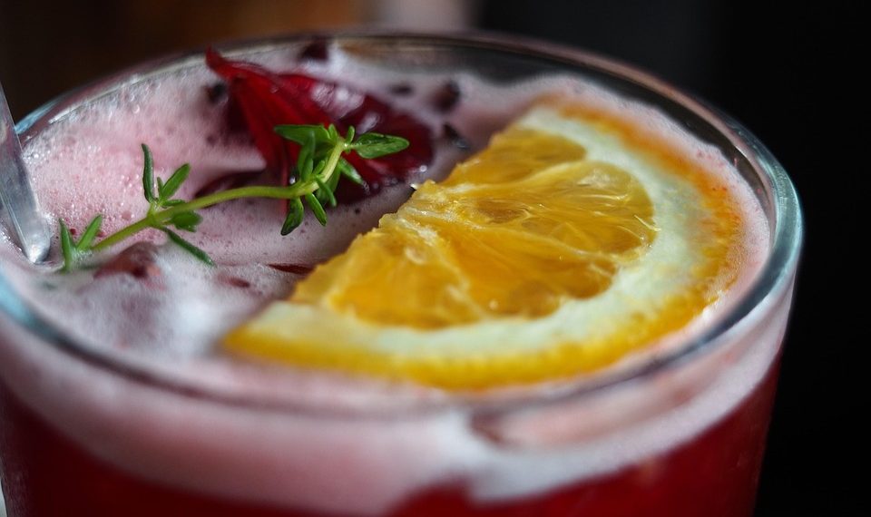 Refreshing hibiscus cocktail with orange slice garnish.
