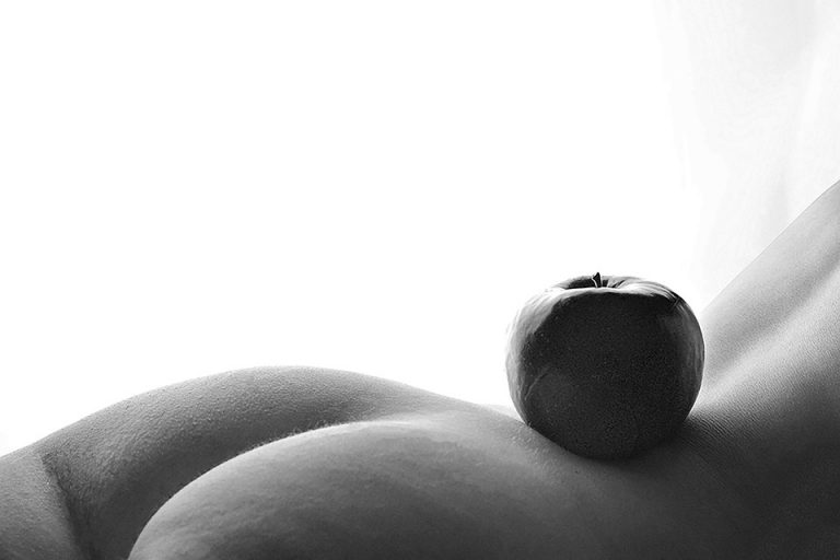 Apple balanced on serene body curve in black and white.