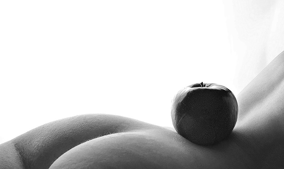 Apple balanced on serene body curve in black and white.
