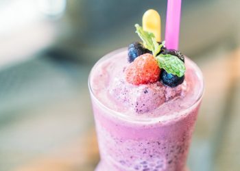 Berry smoothie topped with fresh fruits and mint leaves.