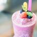 Berry smoothie topped with fresh fruits and mint leaves.