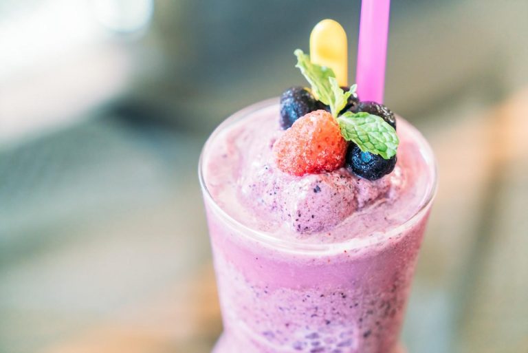 Berry smoothie topped with fresh fruits and mint leaves.