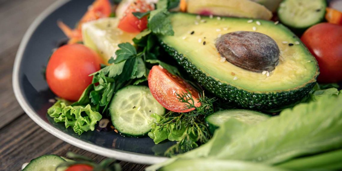 Avocado and fresh vegetables on a salad plate.
