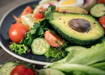 Avocado and fresh vegetables on a salad plate.