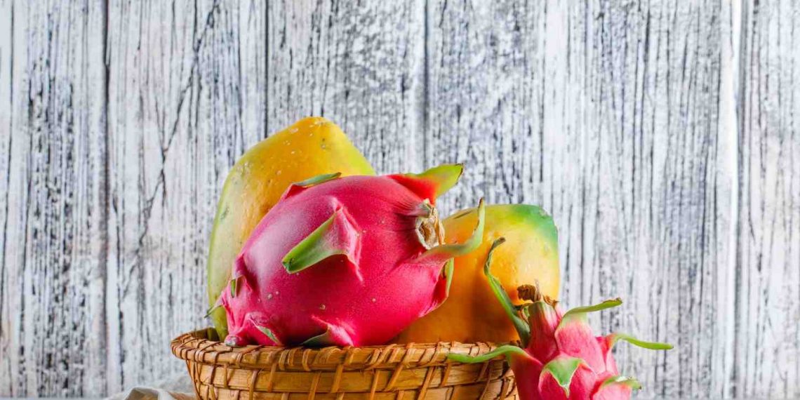 Tropical fruits in a basket against a rustic wooden background.