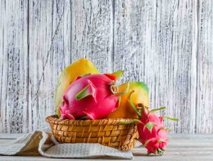 Tropical fruits in a basket against a rustic wooden background.