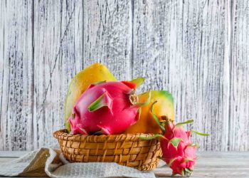 Tropical fruits in a basket against a rustic wooden background.