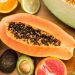 Tropical fruits including papaya, avocado, and citrus slices arranged on a wooden board.