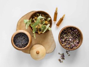 Dried herbs and essential oils in wooden bowls for aromatherapy.