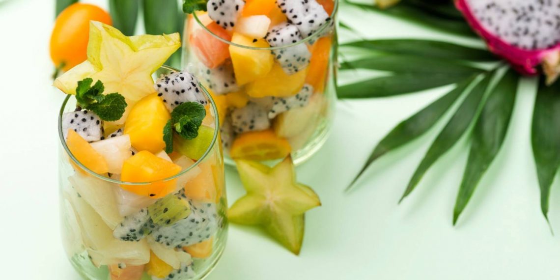 Tropical fruit salad in glasses with starfruit slices and mint.