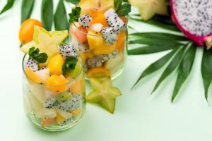 Tropical fruit salad in glasses with starfruit slices and mint.
