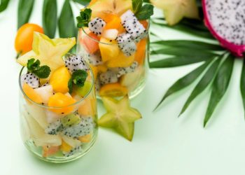 Tropical fruit salad in glasses with starfruit slices and mint.
