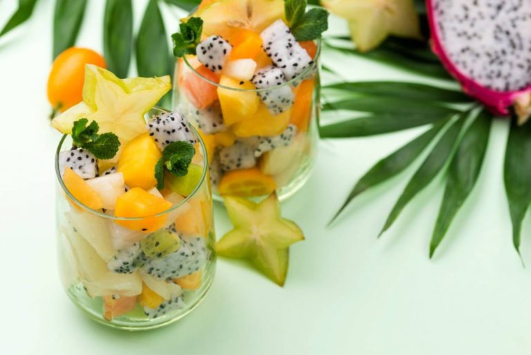 Tropical fruit salad in glasses with starfruit slices and mint.