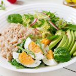 Healthy breakfast bowl with eggs, avocado, greens, and oatmeal.