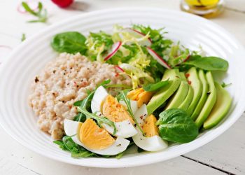Healthy breakfast bowl with eggs, avocado, greens, and oatmeal.