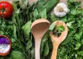 Fresh herbs and vegetables with wooden spoons on burlap.