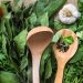 Fresh herbs and vegetables with wooden spoons on burlap.