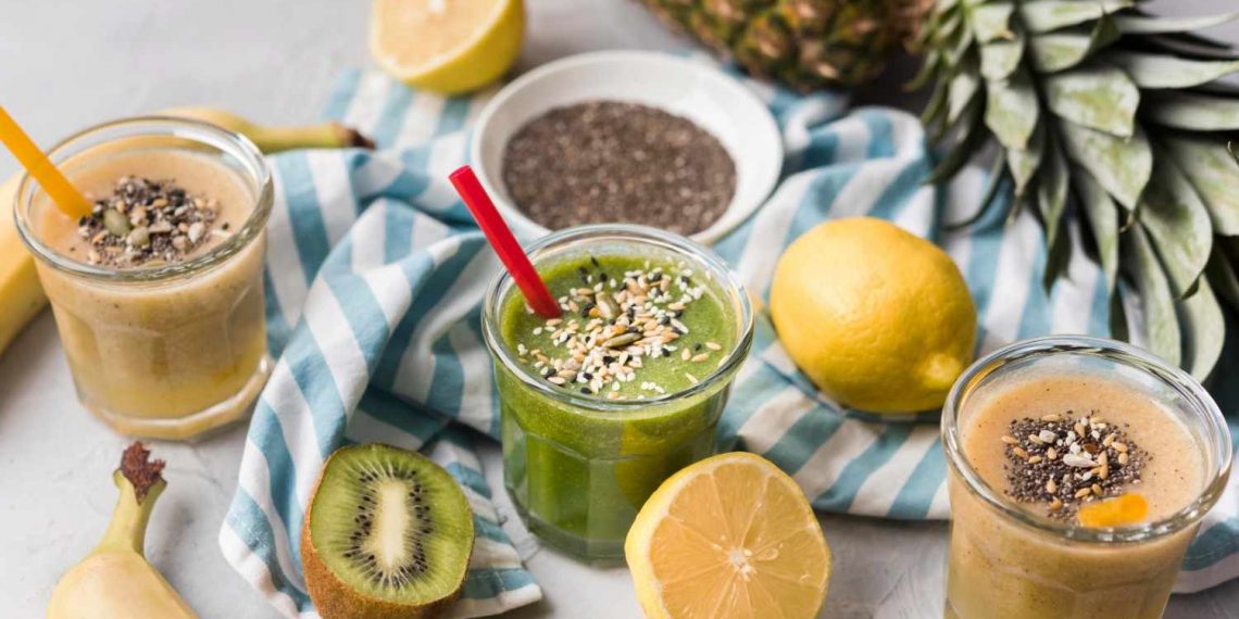 Three healthy smoothies with chia seeds, surrounded by fresh fruits.