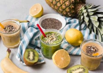 Three healthy smoothies with chia seeds, surrounded by fresh fruits.