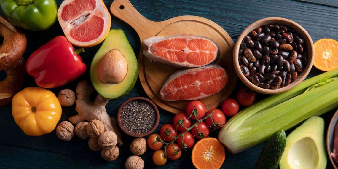 Colorful spread of fresh fruits, vegetables, salmon, and nuts for healthy eating.