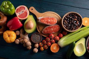 Colorful spread of fresh fruits, vegetables, salmon, and nuts for healthy eating.