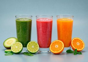 Three colorful smoothies with fresh fruits and mint leaves.