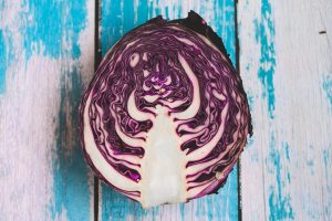 Sliced red cabbage on rustic blue wooden background.