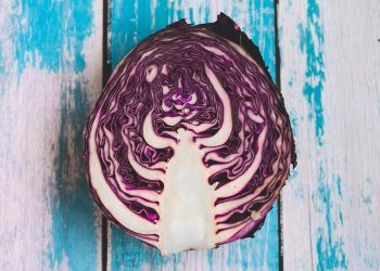 Sliced red cabbage on rustic blue wooden background.