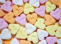 Colorful heart-shaped candies with sweet messages scattered randomly.