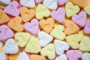 Colorful heart-shaped candies with sweet messages scattered randomly.