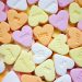 Colorful heart-shaped candies with sweet messages scattered randomly.
