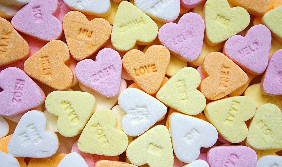 Colorful heart-shaped candies with sweet messages scattered randomly.