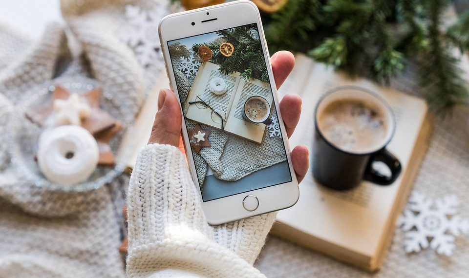 Cozy winter scene captured on smartphone with coffee and book.